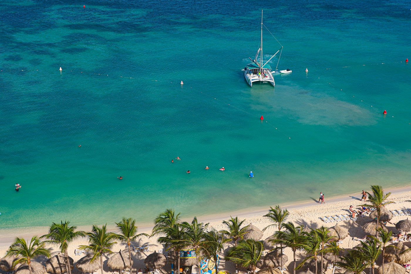 Catamarán navegando sobre agua turquesa cerca de una playa del Caribe
