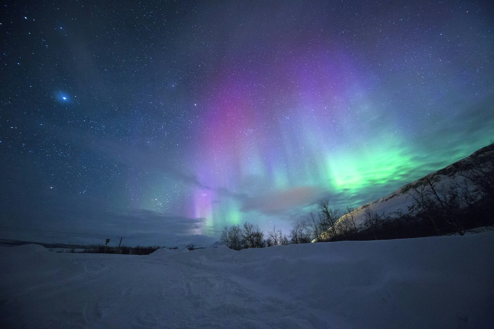 Aurora boreal de colores sobre una montaña nevada cerca de Tromsø, Noruega