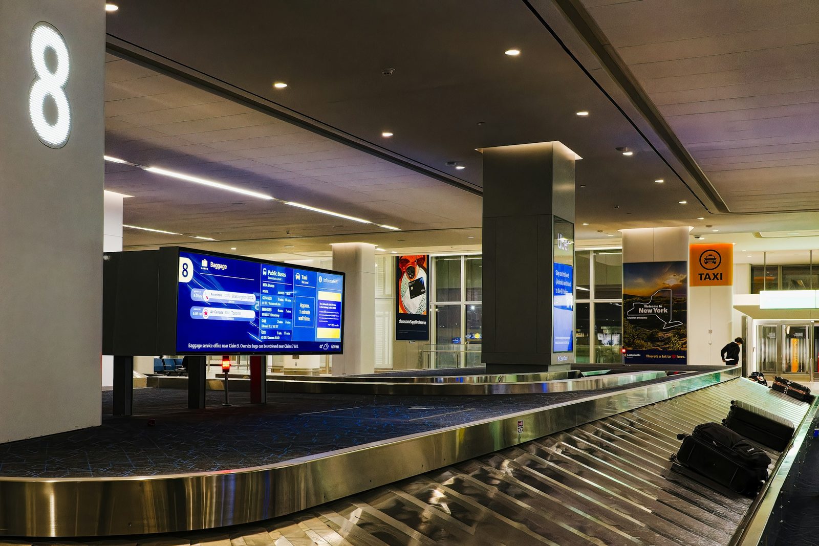 Sala de reclamo de equipaje de un aeropuerto con la banda y una pantalla de vuelos