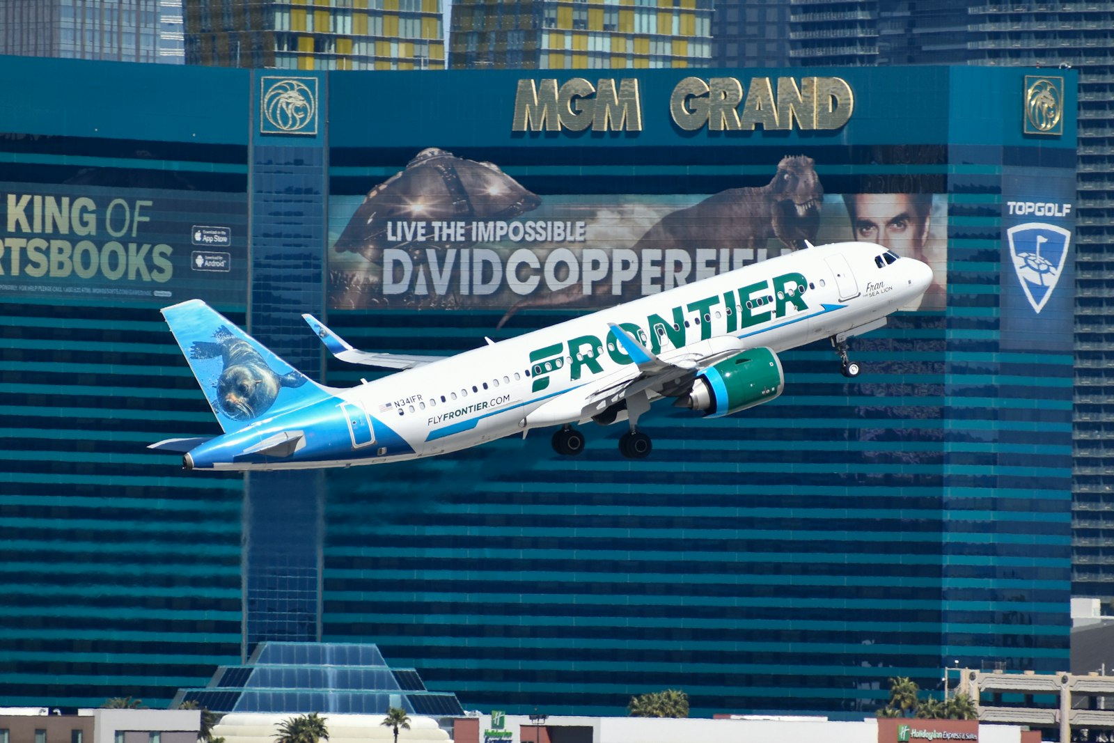 Avión de Frontier Airlines despegando frente a un gran hotel de Las Vegas