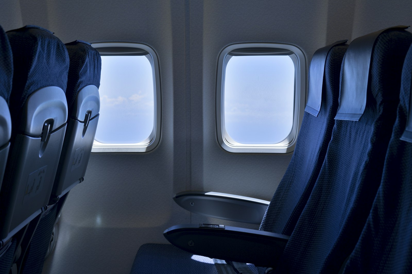 Fila de asientos de avión junto a las ventanillas, con el espacio para el artículo personal debajo