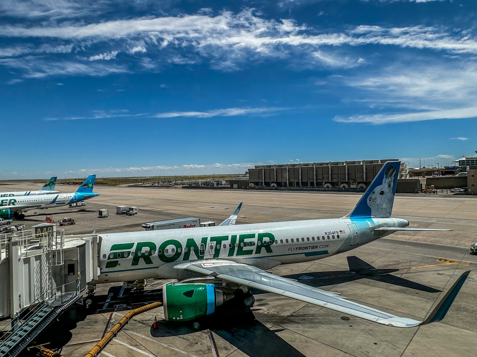 Avión Airbus de Frontier Airlines con su pintura verde y blanca estacionado junto a la puerta de embarque
