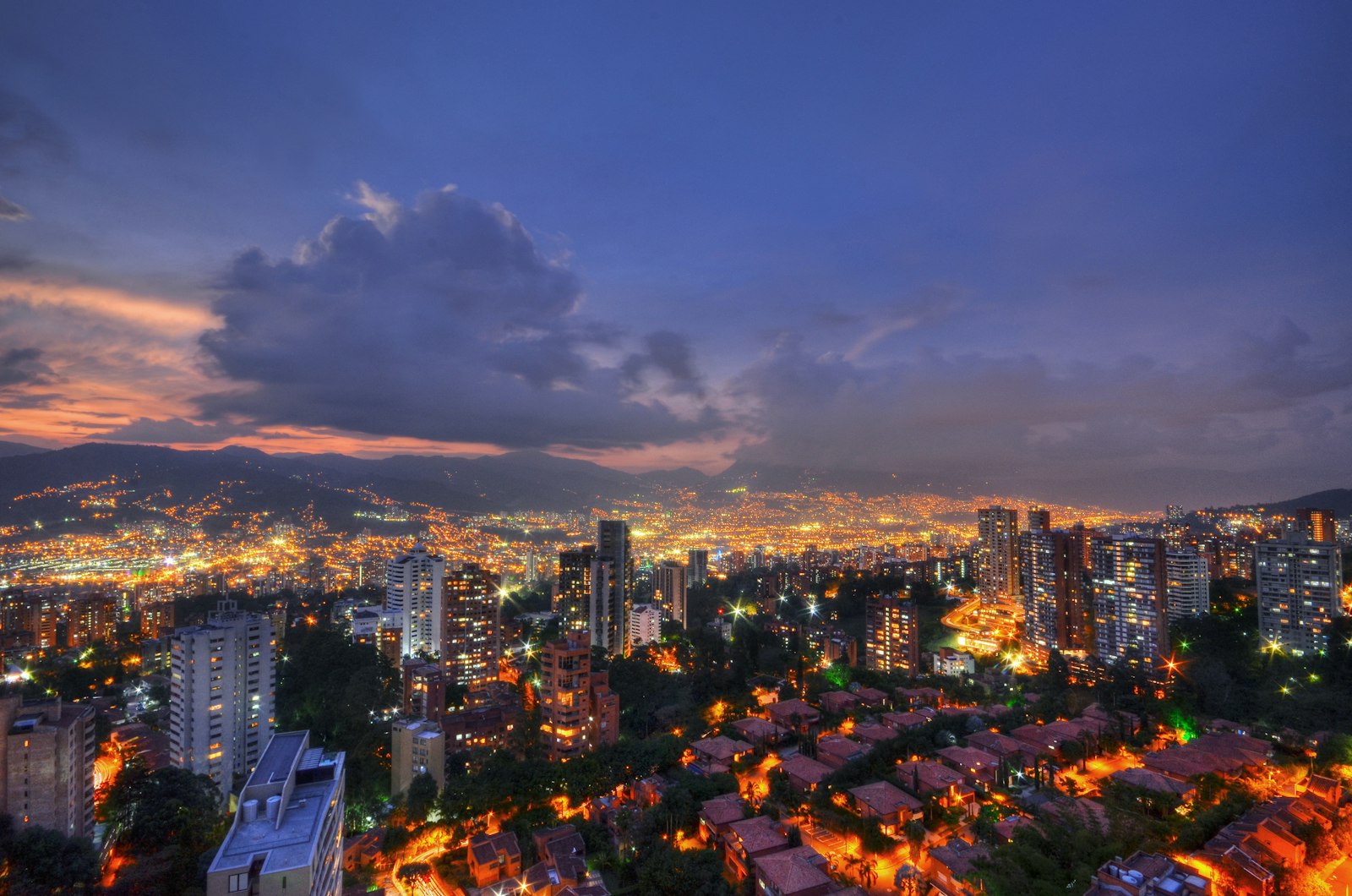 Vista nocturna de Medellín con las luces de la ciudad y las montañas al fondo