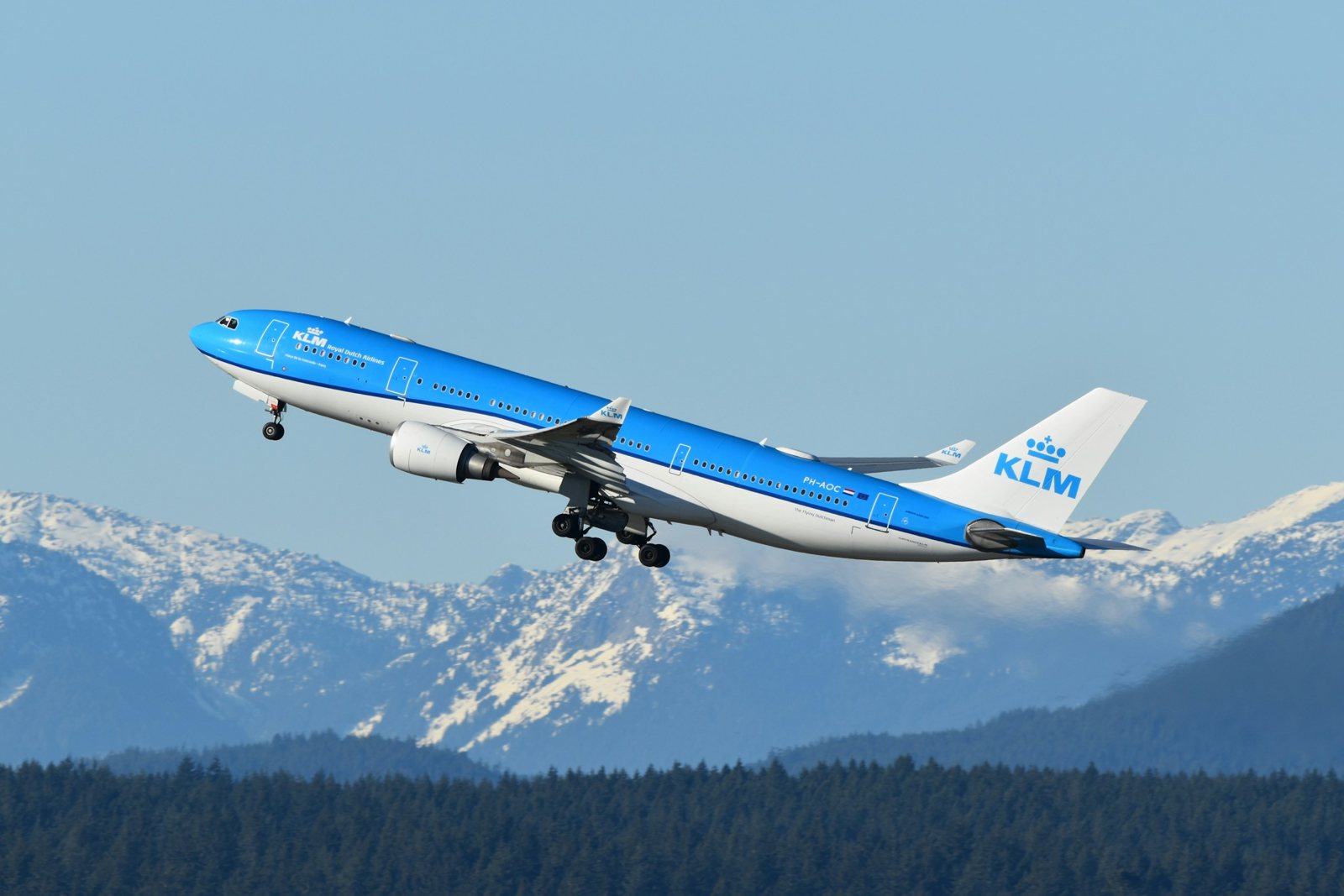 Avión de KLM despegando con montañas nevadas al fondo