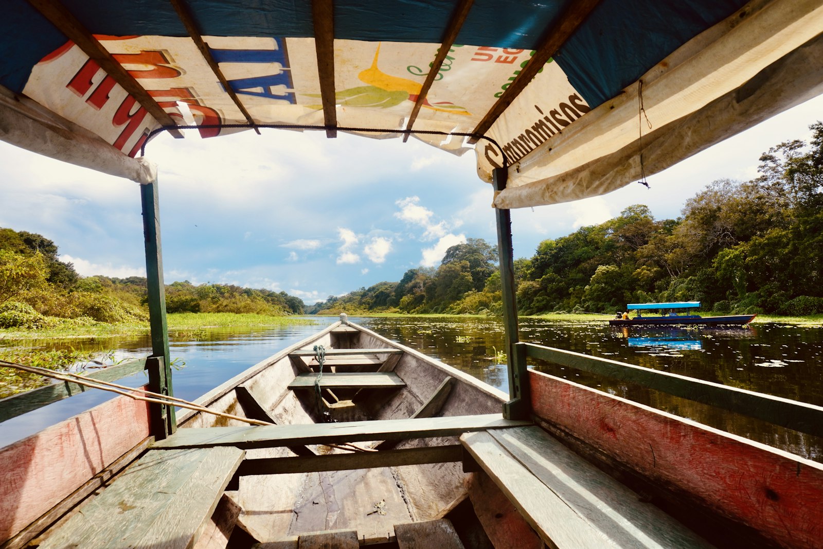 Canoa de madera navegando por un río de la Amazonía colombiana rodeado de selva