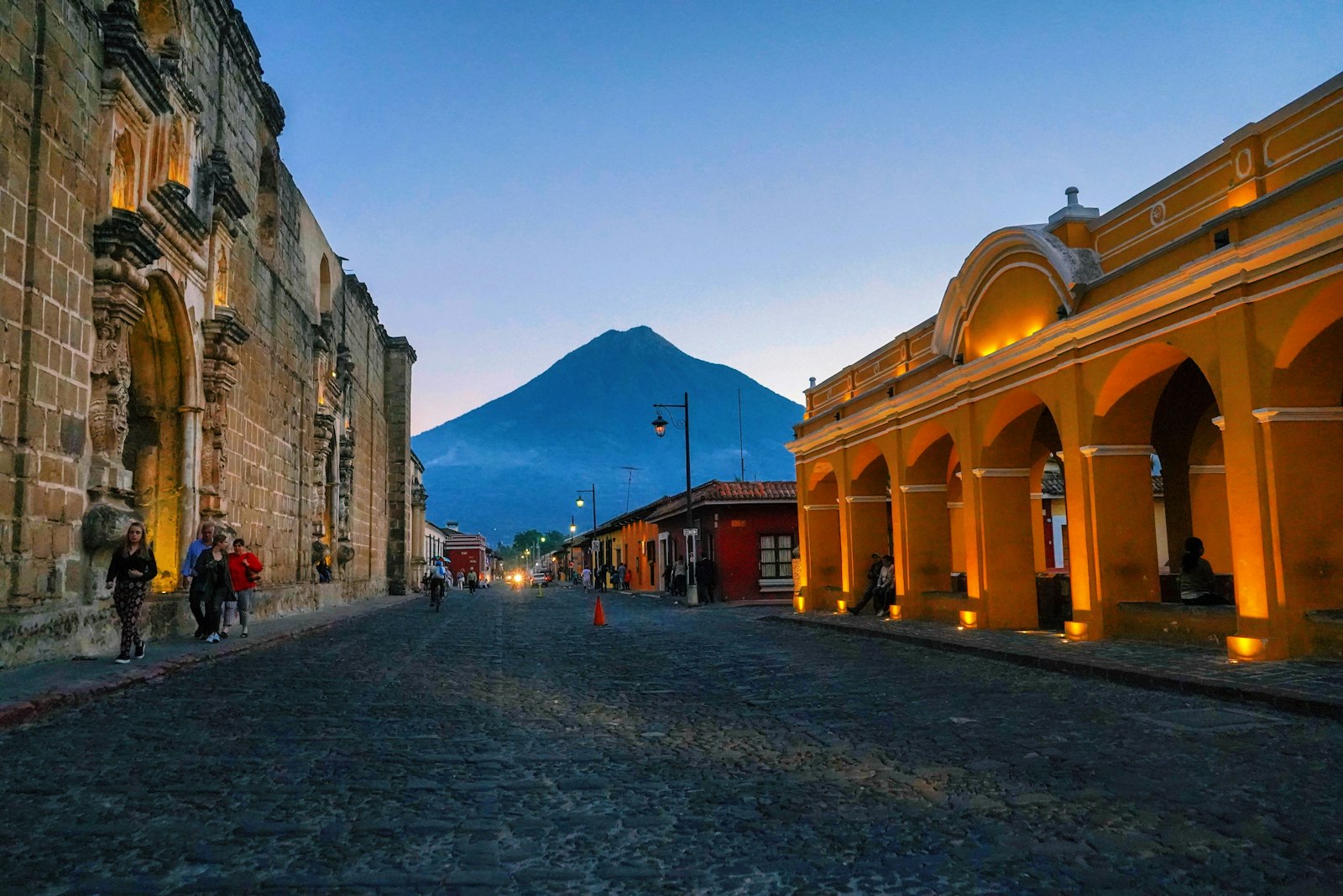 Calle empedrada de Antigua Guatemala con edificios coloniales y el volcán de Agua al fondo