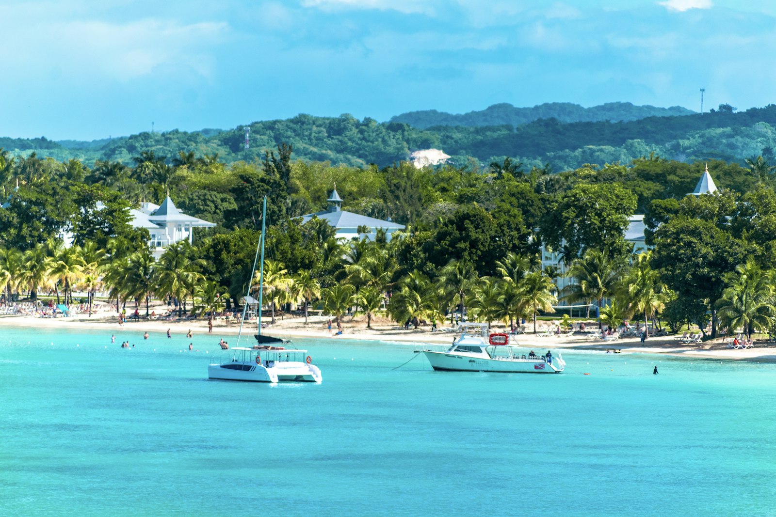 Veleros y lanchas anclados frente a una playa de arena blanca con palmeras en Negril, Jamaica