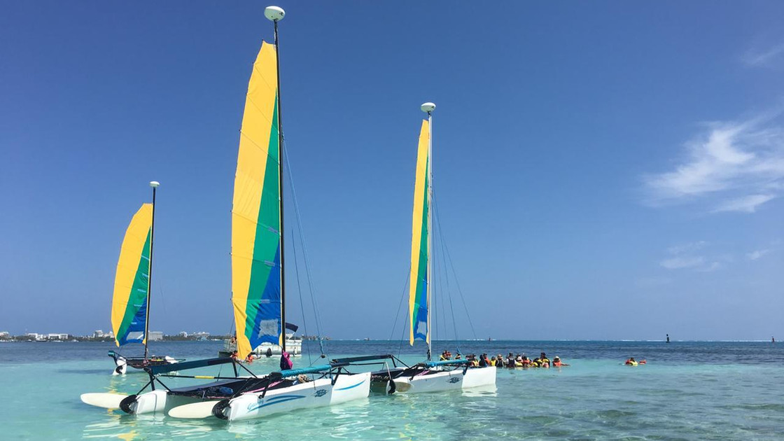 Catamaranes de vela amarilla fondeados sobre agua turquesa en San Andrés, con un grupo haciendo snorkel