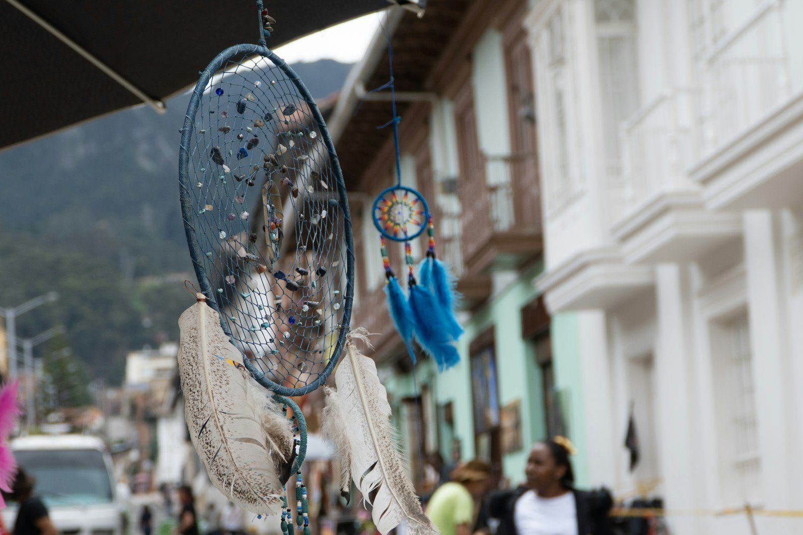 Puesto de artesanías con atrapasueños colgados en una calle colonial de casas de colores