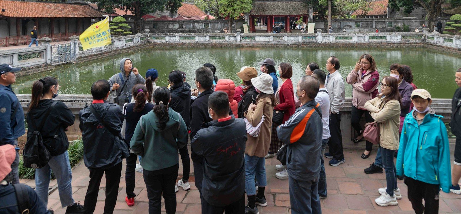 Grupo de viajeros escuchando a su guía junto a un estanque, en una visita a pie