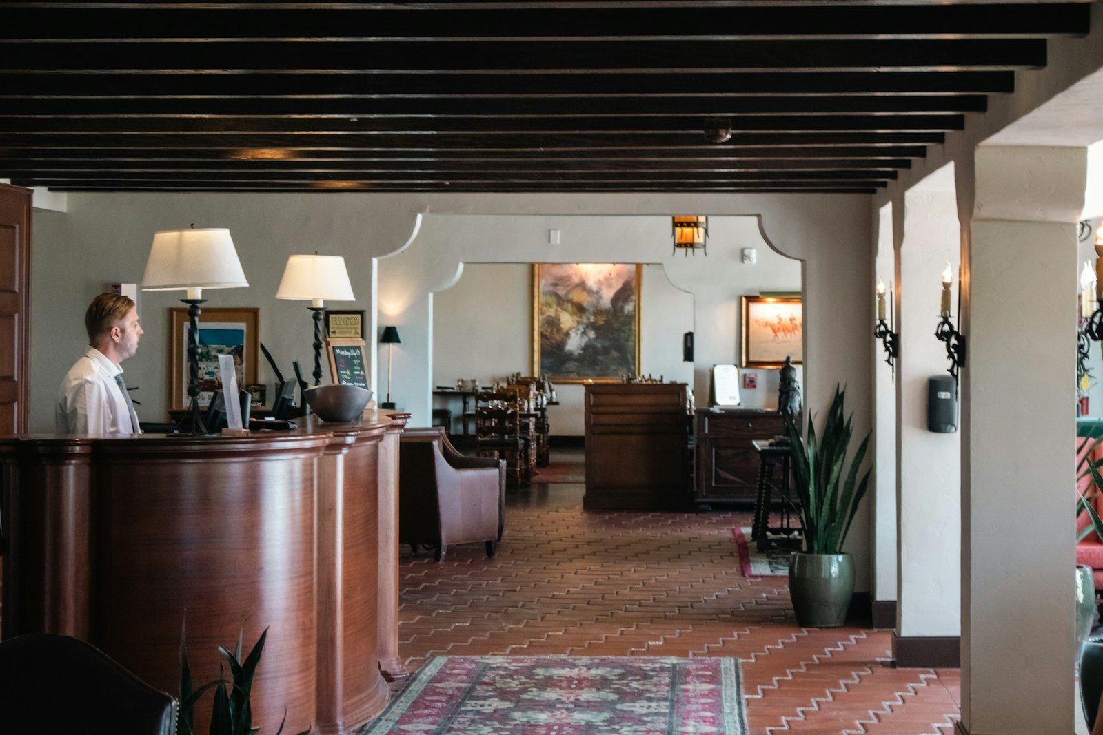 Recepción de un hotel con personal atendiendo detrás del mostrador de madera