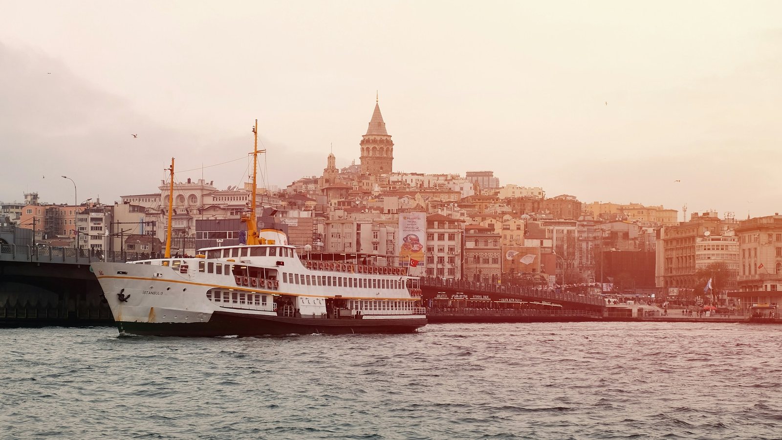 Ferry tradicional cruzando el Bósforo frente a la torre de Gálata al atardecer