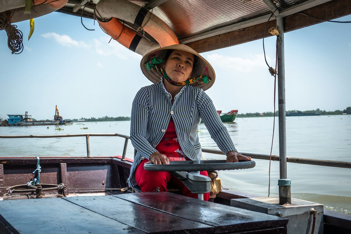 Mujer con sombrero cónico remando una barca en un canal del delta del Mekong