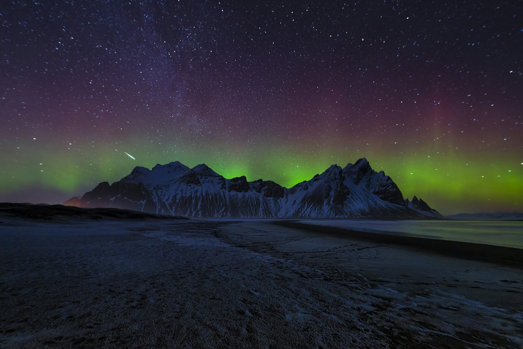 Aurora boreal verde sobre una montaña nevada de Islandia