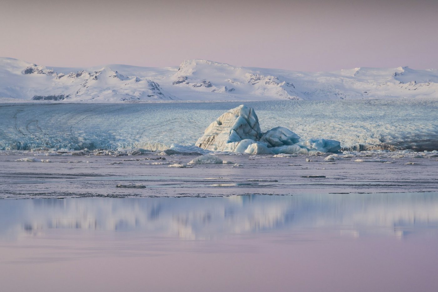Iceberg flotando en la laguna glaciar de Jökulsárlón frente a las montañas nevadas