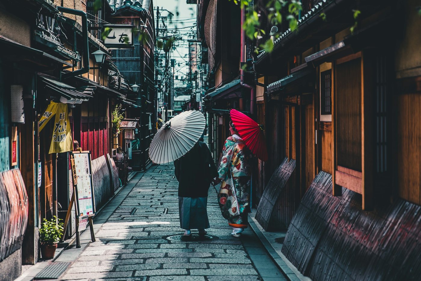 Viajeras con kimono y sombrillas en una calle de madera de Kioto