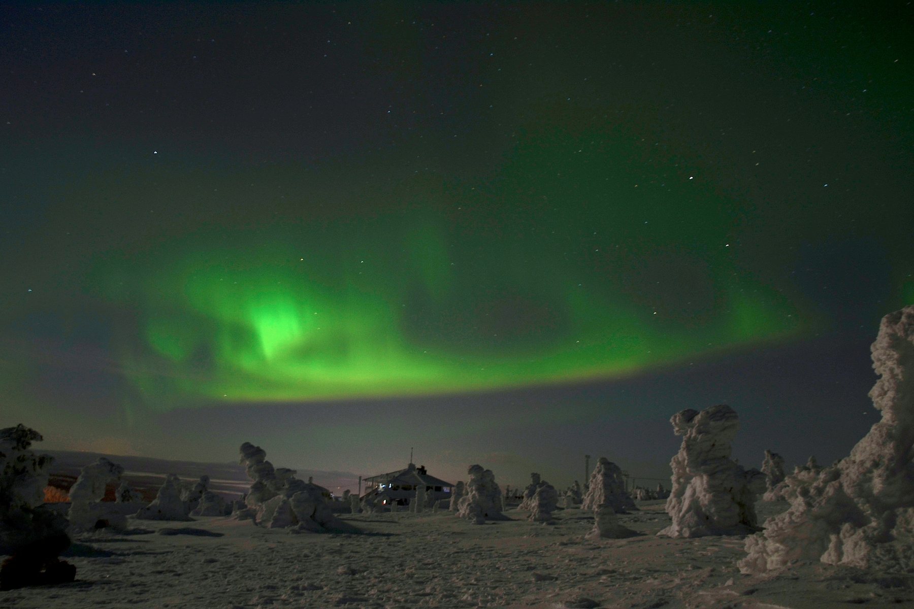 Aurora boreal verde sobre una colina nevada de Laponia, en Finlandia