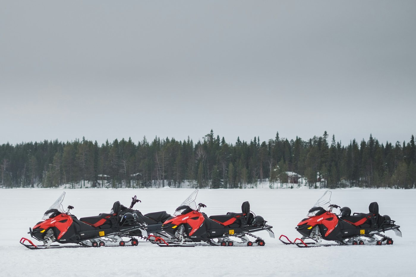 Tres motos de nieve rojas sobre un lago congelado de Laponia