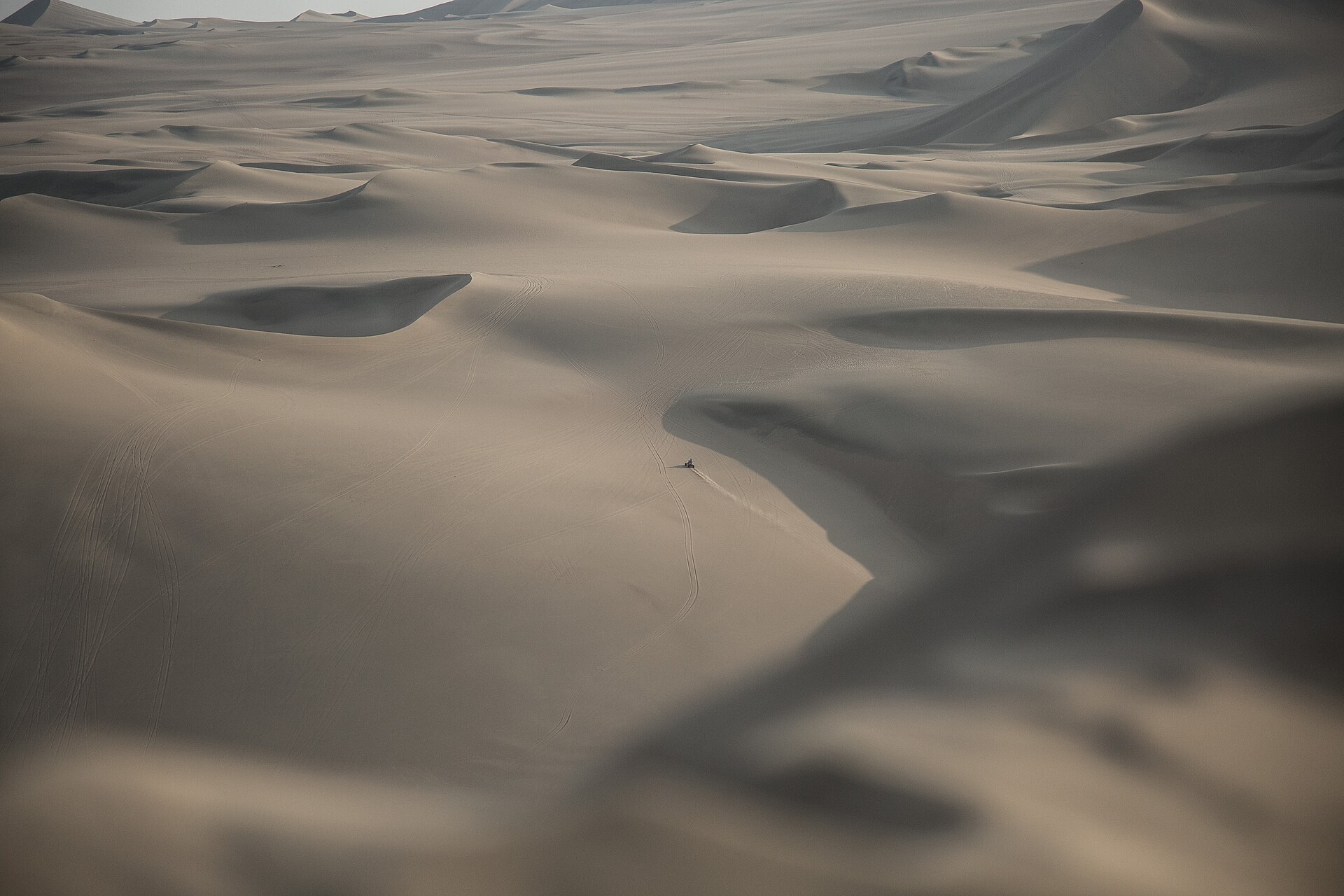 Dunas del desierto de Ica con un buggy a lo lejos