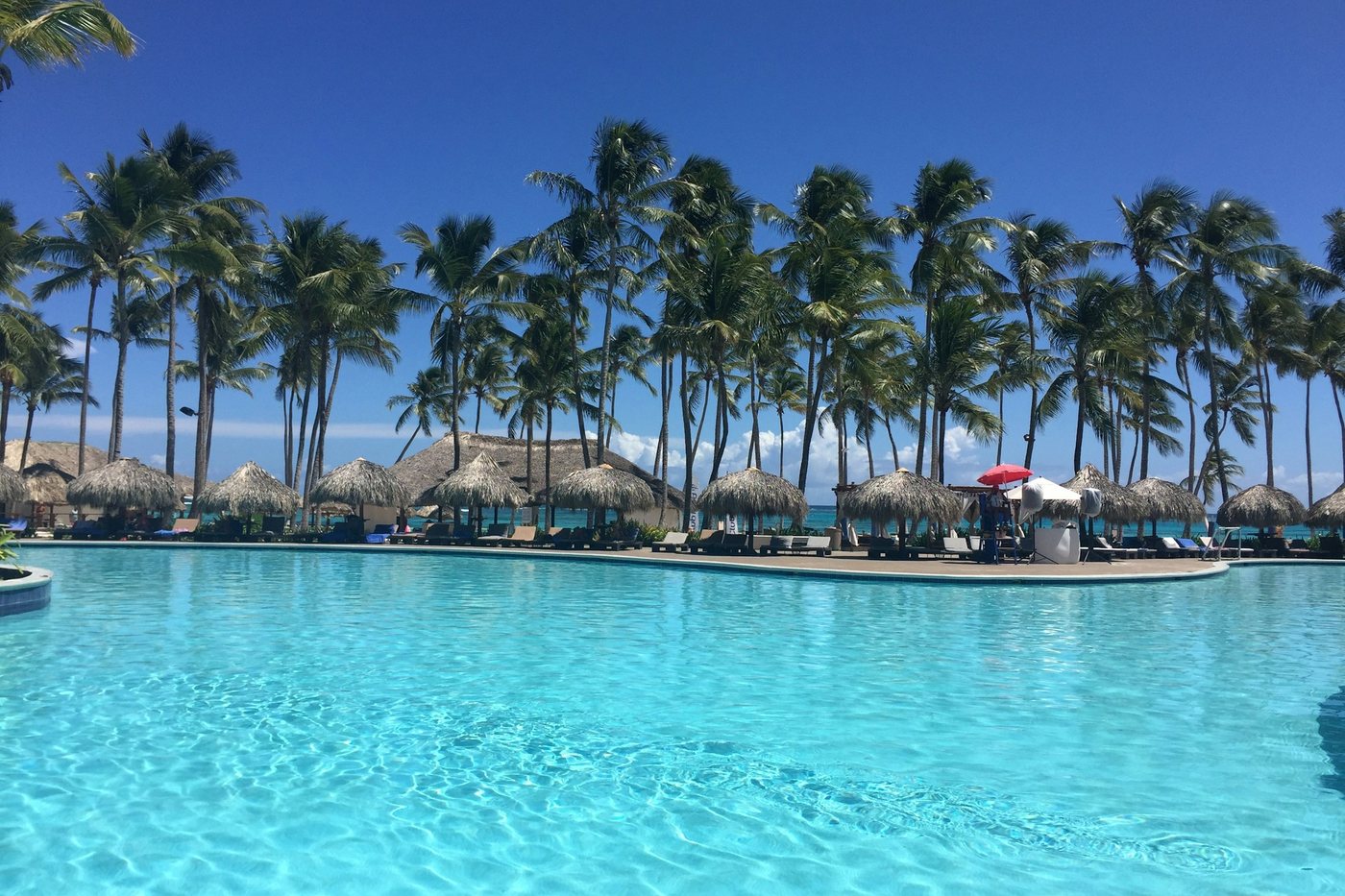 Piscina de un resort rodeada de palmeras y sombrillas de palma