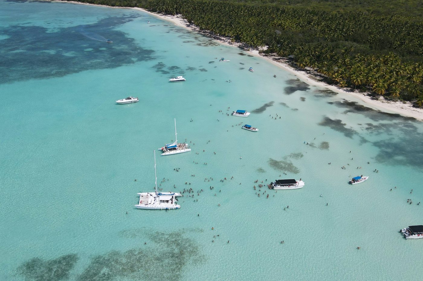 Catamaranes y lanchas anclados en aguas poco profundas y cristalinas cerca de la costa