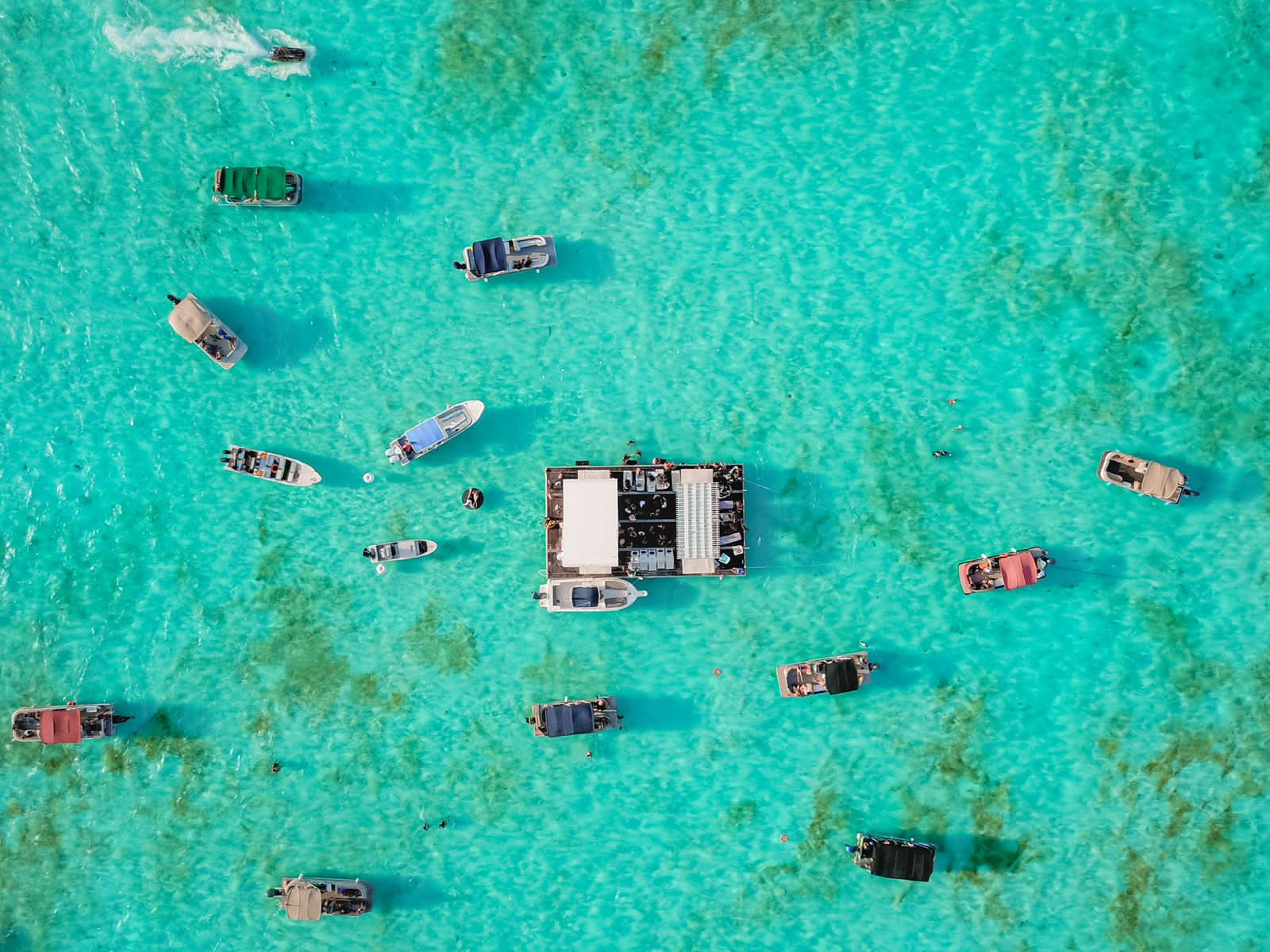 Lanchas fondeadas sobre agua turquesa poco profunda, vistas desde el aire