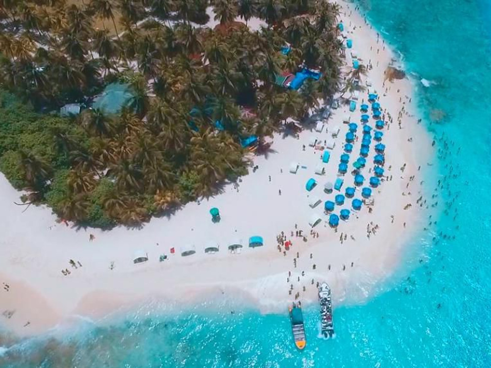 Vista aérea de Johnny Cay: la playa de arena blanca, las carpas azules y las lanchas atracadas
